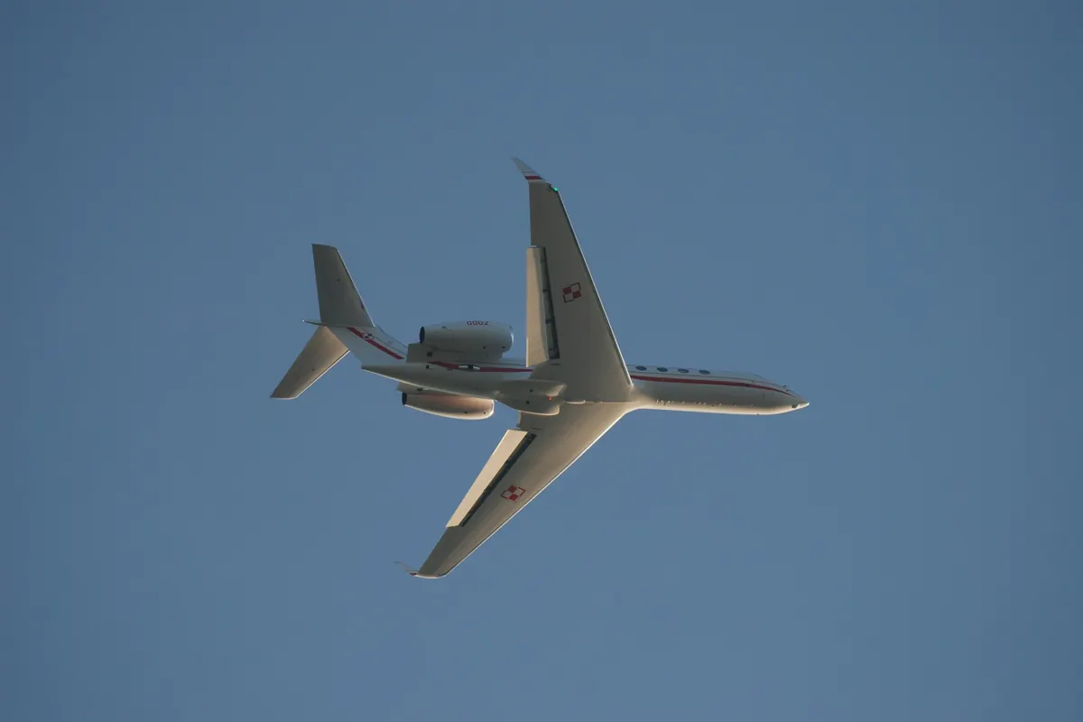 Business jet seen from below in flight against a clear blue sky